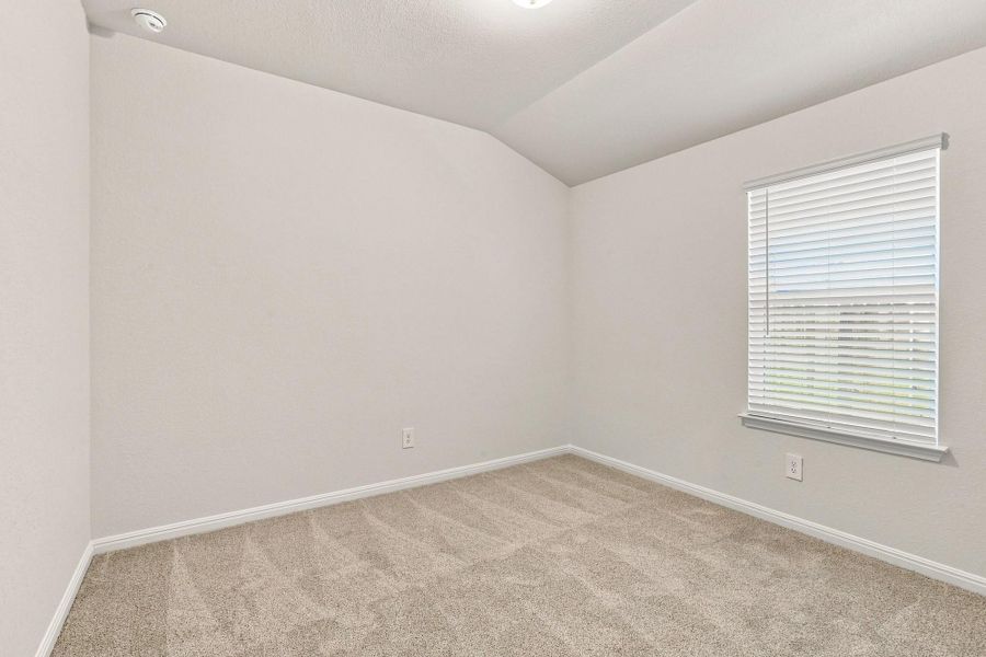 Vaulted ceilings and plush carpeting define this versatile secondary bedroom space.