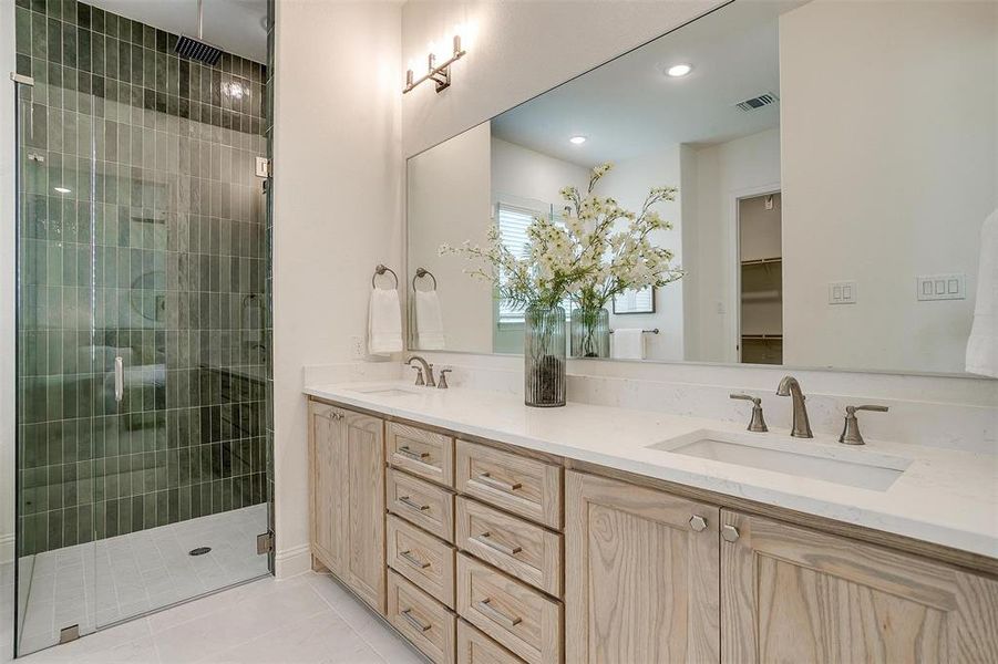 Bathroom with vanity, walk in shower with standard shower head and rain head, freestanding bathtub, and beautiful green tile that compliments the natural stained cabinets.