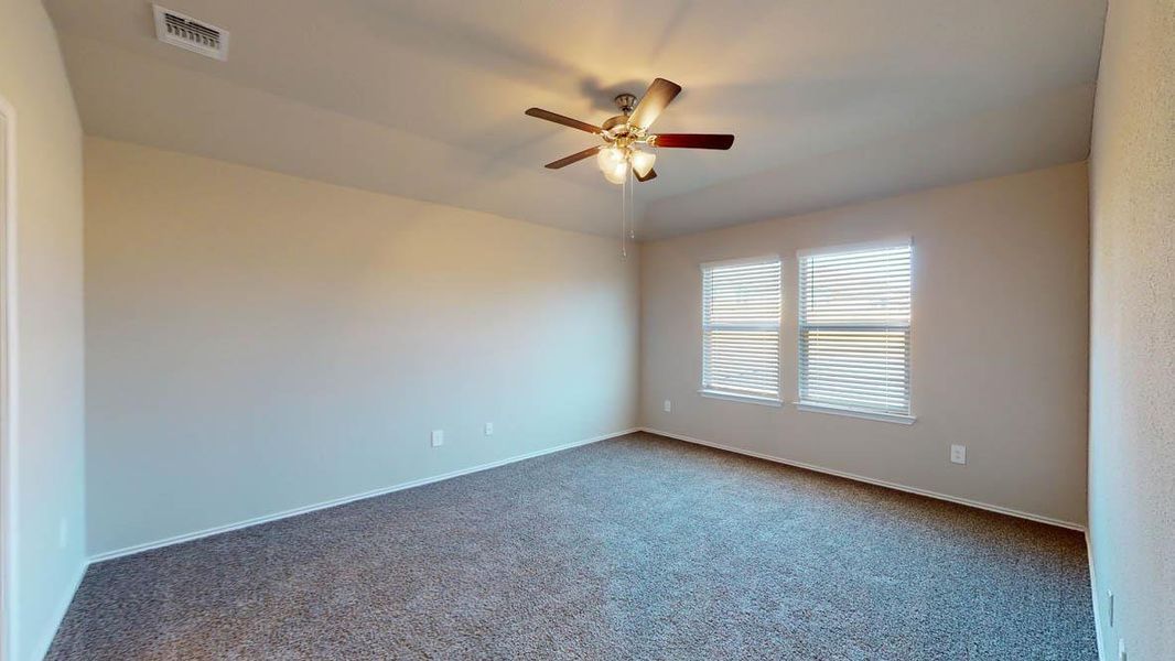 Carpeted empty room featuring ceiling fan and baseboards