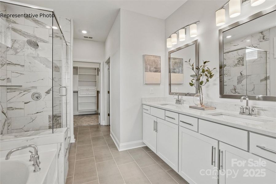 Luxurious primary bathroom features dual sinks and large walk-in closet with upgraded shelving Luxurious primary bathroom features dual sinks and large walk-in closet with upgraded shelving