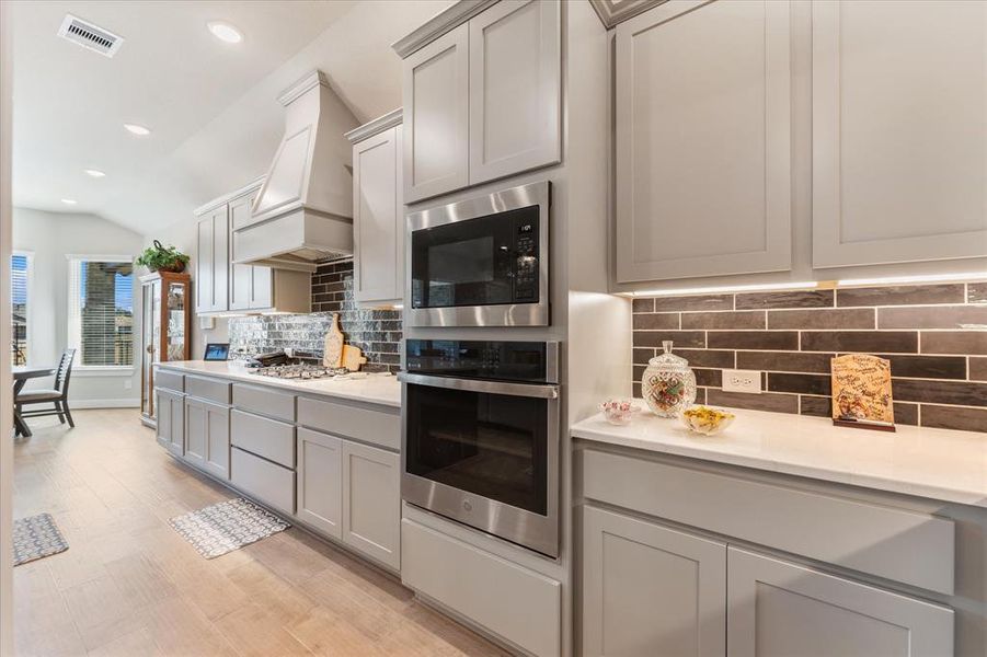 Upgraded cabinets with under-cabinet lighting, soft-close hinges, stacked built-in oven and microwave and standalone vent hood