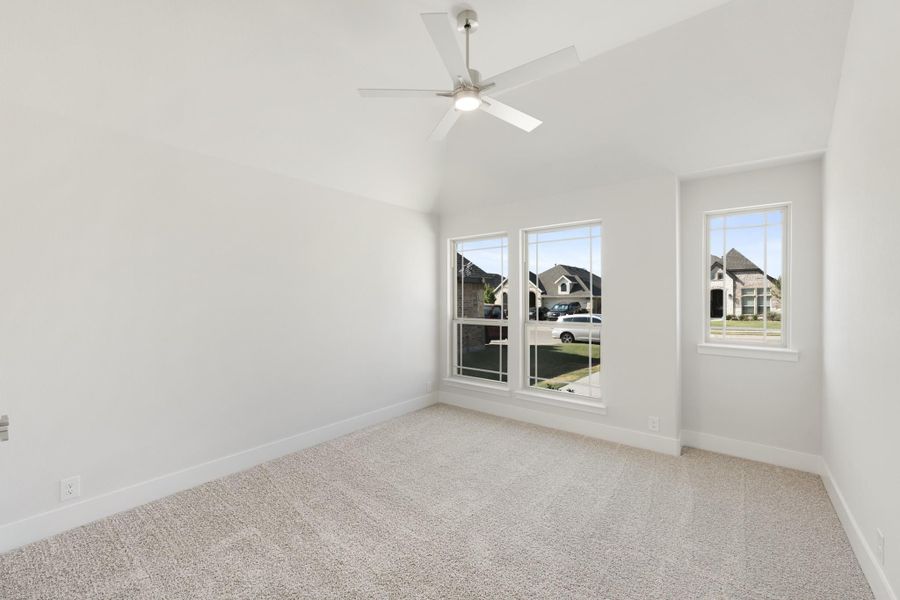 Empty bedroom with vaulted ceiling, ceiling fan, carpet flooring, and two windows overlooking neighborhood homes. Empty bedroom with vaulted ceiling, ceiling fan, carpet flooring, and two windows overlooking neighborhood homes.