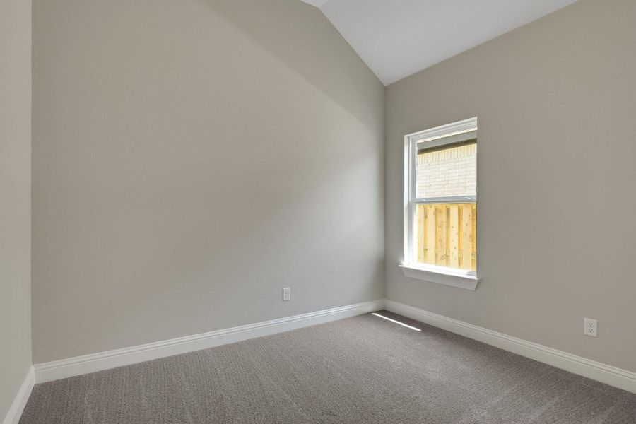 Unfurnished room featuring dark carpet, baseboards, and vaulted ceiling