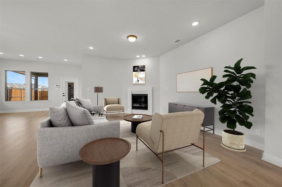 Living room featuring light wood finished floors, a glass covered fireplace, and recessed lighting