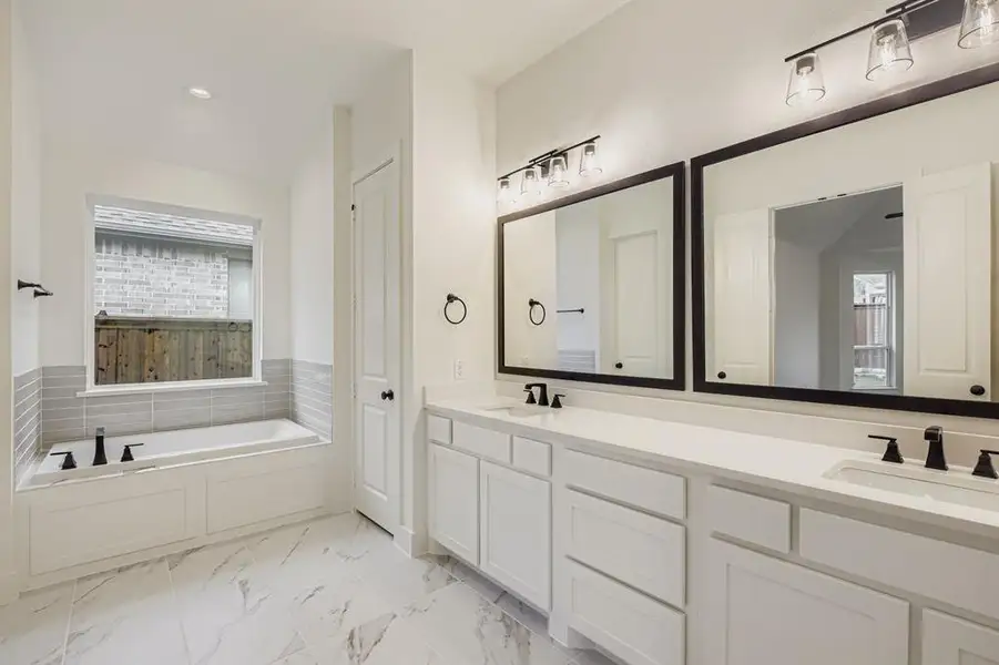 Full bathroom with a bath, double vanity, recessed lighting, and light marble finish flooring