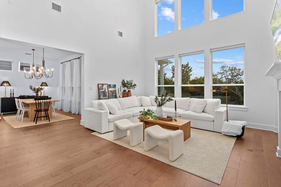 Living room featuring a towering ceiling, a chandelier, and light wood-type flooring