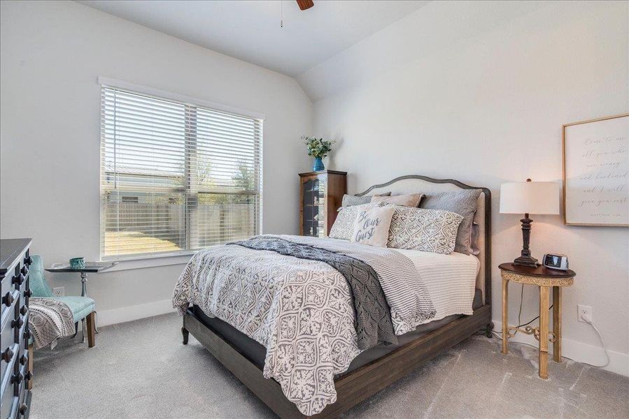 Bedroom featuring vaulted ceiling, light carpet, and ceiling fan Bedroom featuring vaulted ceiling, light carpet, and ceiling fan