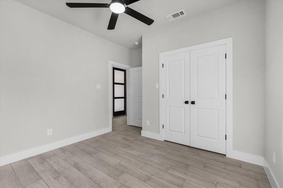 Unfurnished bedroom featuring light wood finished floors, a closet, visible vents, and baseboards