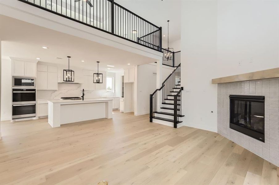 Living room featuring a towering ceiling, an inviting chandelier, light hardwood / wood-style flooring, and a tile fireplace