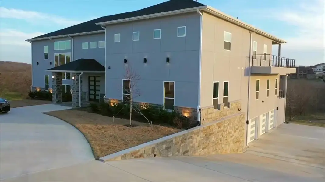 View of property exterior with stone siding, stucco siding, concrete driveway, and a garage