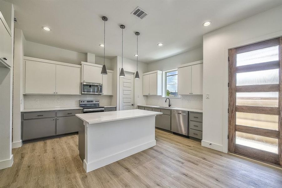 Kitchen featuring gray cabinets, a center island, white cabinetry, and stainless steel appliances