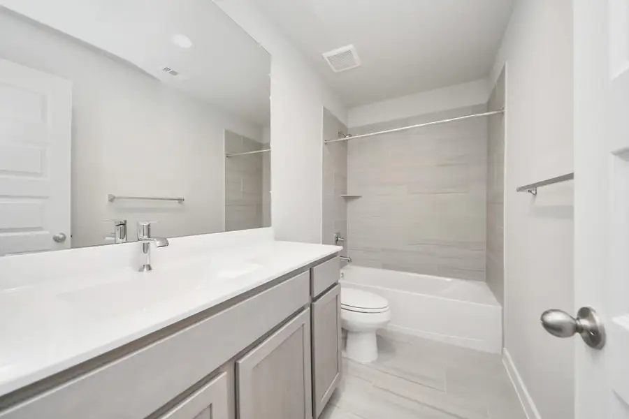Secondary bath features tile flooring, bath/shower combo with tile surround, light stained wood cabinets, beautiful light countertop. Secondary bath features tile flooring, bath/shower combo with tile surround, light stained wood cabinets, beautiful light countertop.