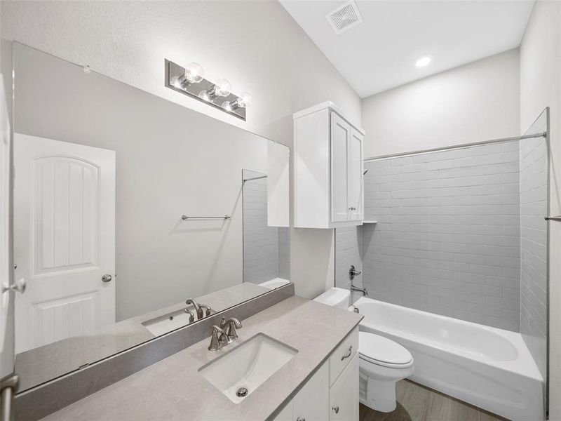Bathroom featuring visible vents, toilet, shower / bath combination, vanity, and wood finished floors