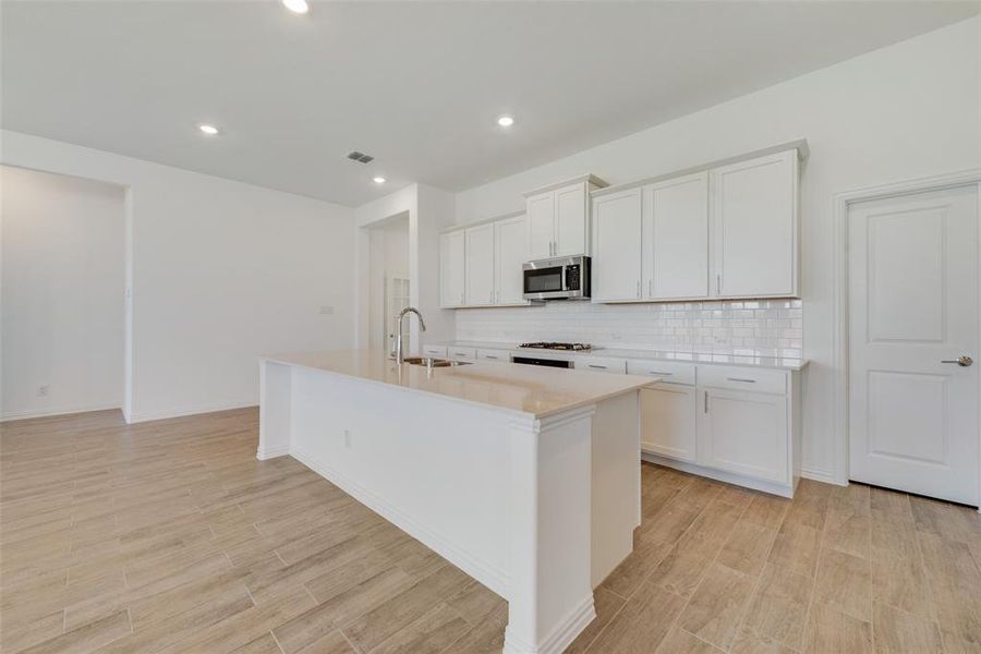 Kitchen featuring sink, a kitchen island with sink, and white cabinets