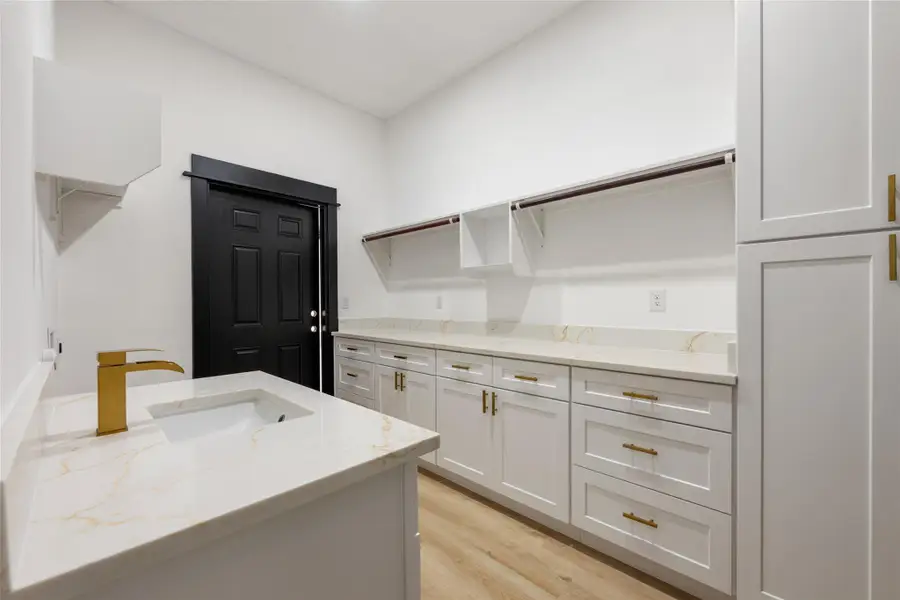 Laundry area with light wood-type flooring and a sink Laundry area with light wood-type flooring and a sink
