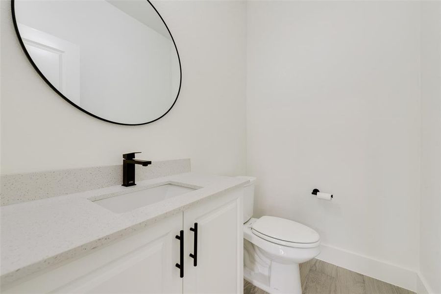 Bathroom featuring baseboards, vanity, toilet, and wood finished floors