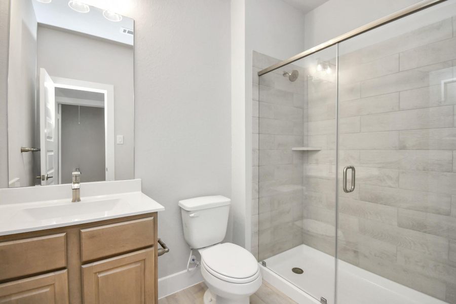 Secondary bath features tile flooring, bath/shower combo with tile surround, light stained wood cabinets, beautiful light countertop. Secondary bath features tile flooring, bath/shower combo with tile surround, light stained wood cabinets, beautiful light countertop.
