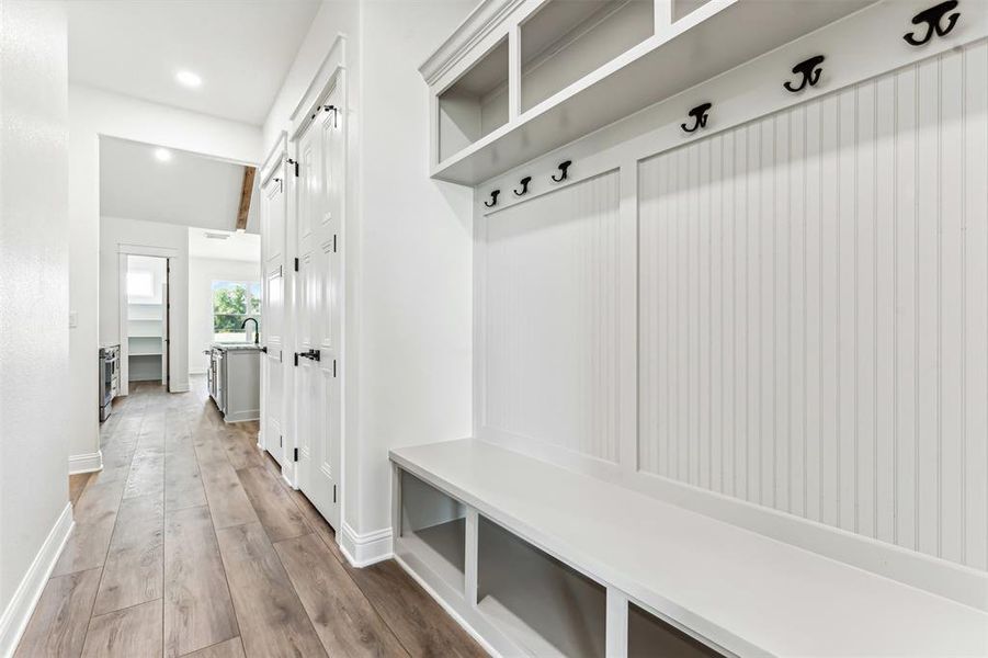 Mudroom entry from garage featuring sink and light hardwood / wood-style flooring