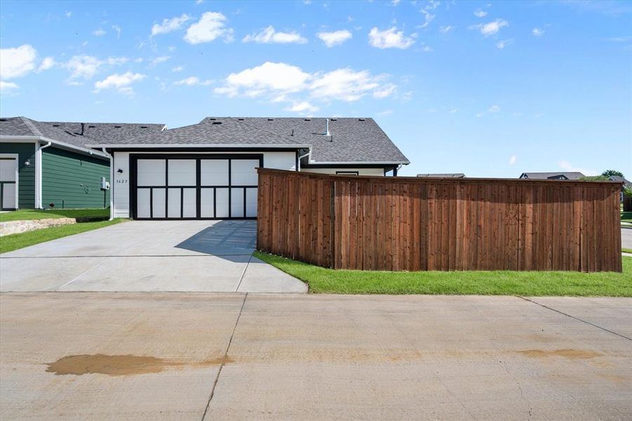 View of alley entrance to access the 2 Car Garage, quiet garage door opener, attic accessibility, concrete driveway, rain gutters, and privacy fence with side gate access to the backyard. Extra parking in the driveway.
