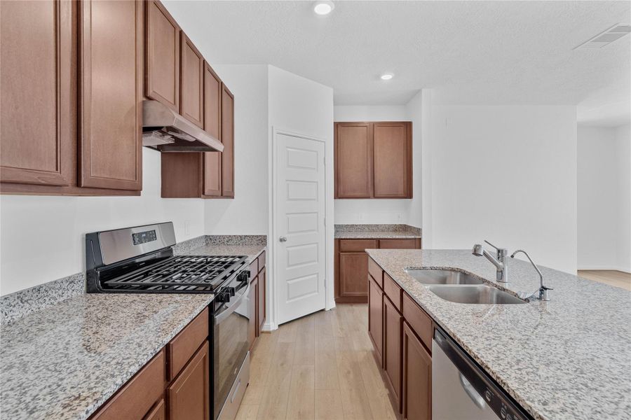 A true chef’s dream, this expansive kitchen boasts high ceilings, rich stained wood cabinets, Granite countertops in Caramel Cream, stainless steel appliances, recessed lighting, extended counter space, an island with added breakfast bar, and a walk-in pantry—all with a clear view of the spacious family room.