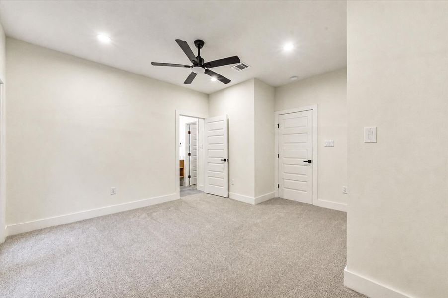 Spacious 3rd bedroom with plush carpeting, recessed lighting, and a modern ceiling fan, featuring two white panel doors for added elegance and functionality.