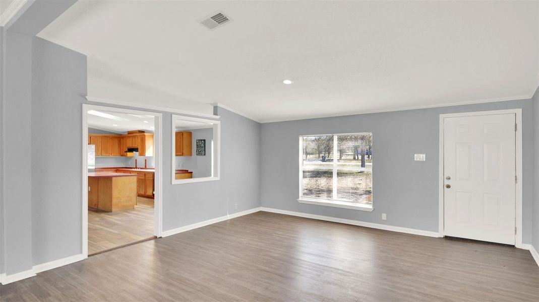 Unfurnished living room featuring light wood-style floors, ornamental molding, and recessed lighting