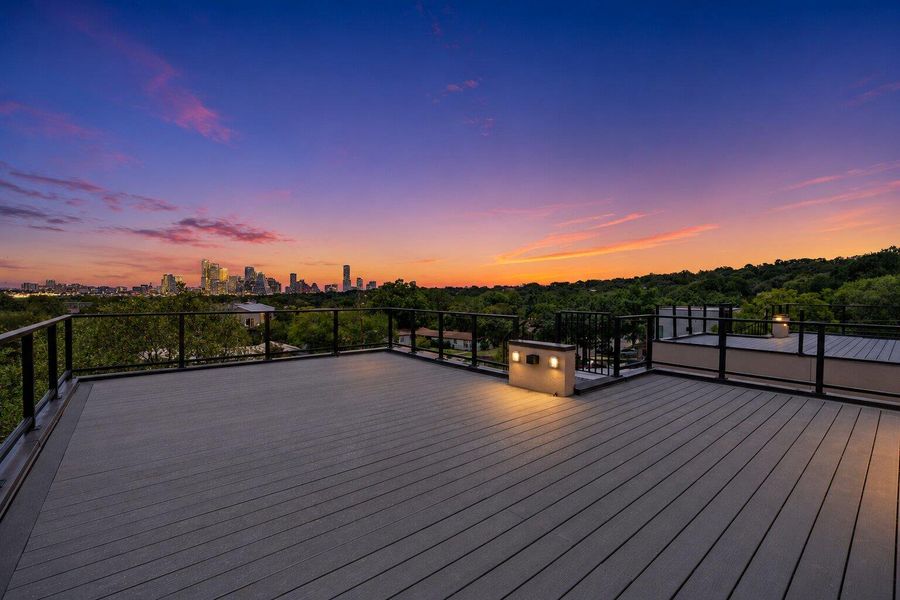 An inviting deck offers panoramic city skyline and verdant treetop views under a dramatic evening sky. An inviting deck offers panoramic city skyline and verdant treetop views under a dramatic evening sky.
