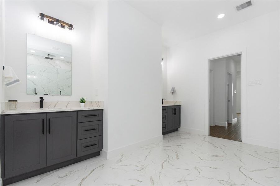 Double vanity with dark color custom self-closing wood cabinets made on site.  Beautiful marble style quartz countertops, oversized mirorrs, and modern plumbing and lighting fixtures.