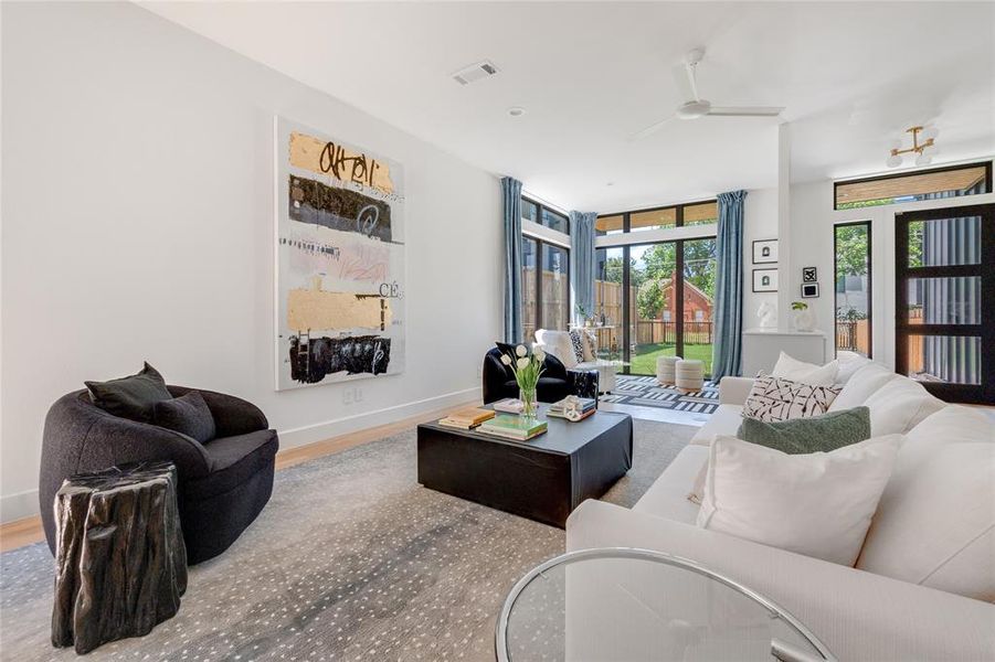 Living room with floor to ceiling windows, wood-type flooring, and ceiling fan