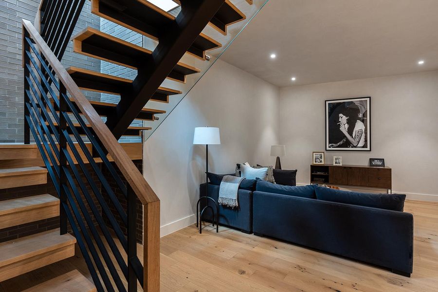 A modern staircase with sleek wood treads and metal railings complements the naturally illuminated living area. A modern staircase with sleek wood treads and metal railings complements the naturally illuminated living area.