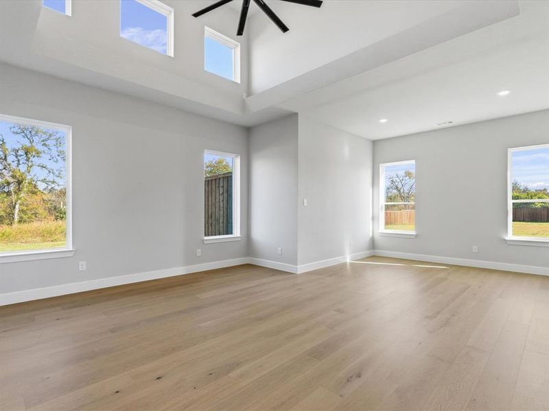 Unfurnished room featuring plenty of natural light, light wood-style floors, and a towering ceiling