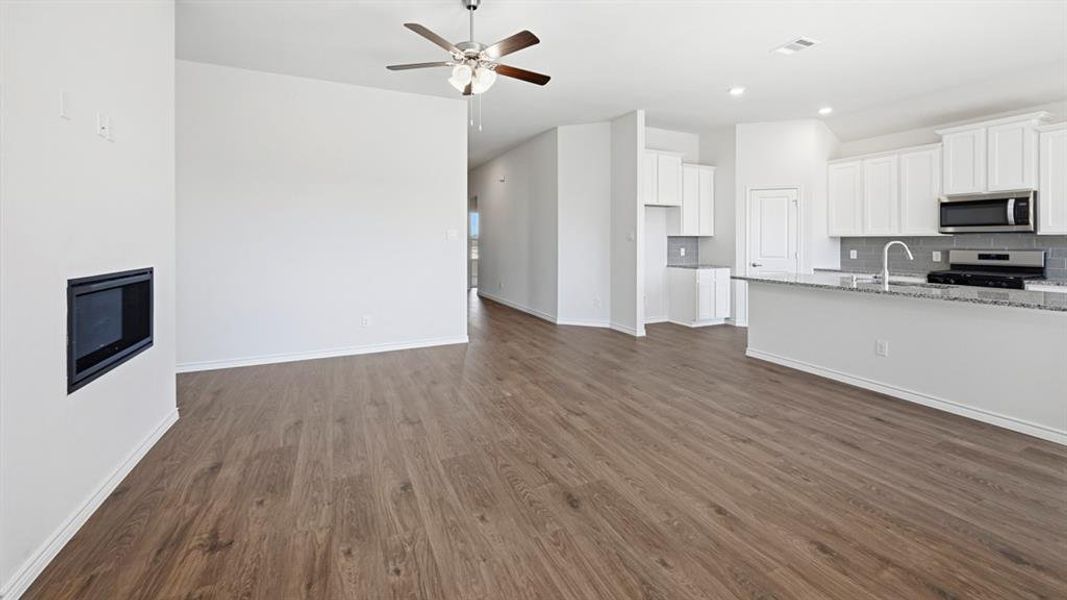 Open-concept living area featuring wood-finish flooring, a contemporary built-in fireplace, and a ceiling fan Open-concept living area featuring wood-finish flooring, a contemporary built-in fireplace, and a ceiling fan