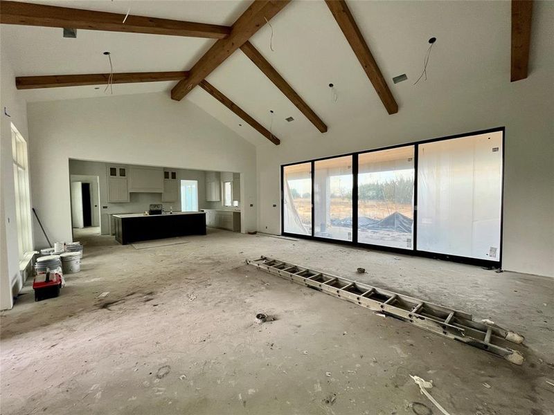 Unfurnished living room with beam ceiling and high vaulted ceiling