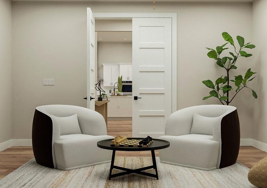 Rendering of the media room showing two
  matching chairs with table, a potted plant, a large white rug, and view to
  the kitchen in the background.