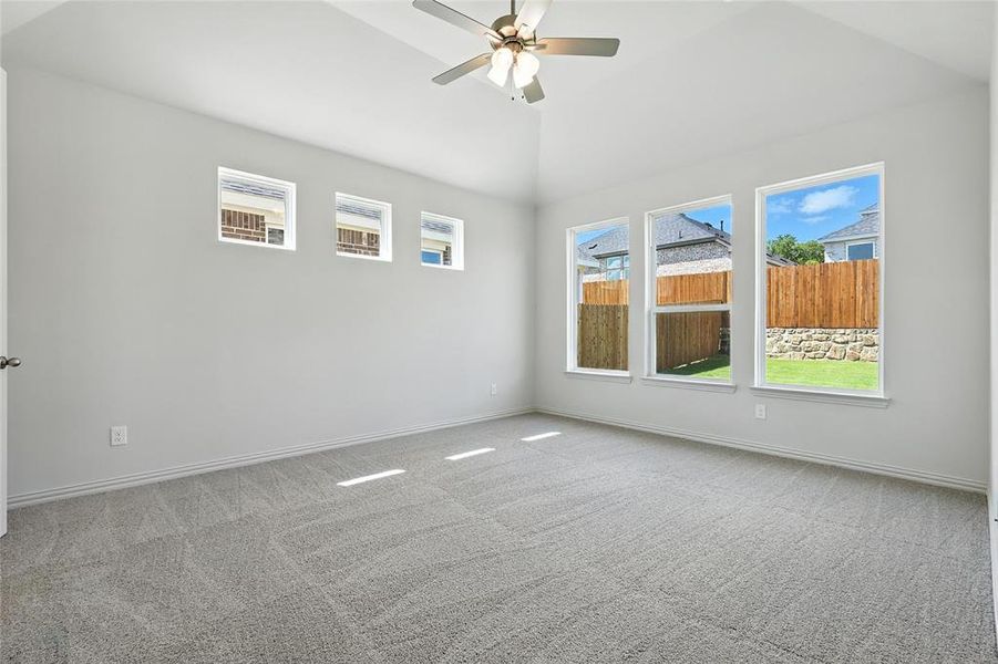 Carpeted empty room featuring ceiling fan and lofted ceiling Carpeted empty room featuring ceiling fan and lofted ceiling