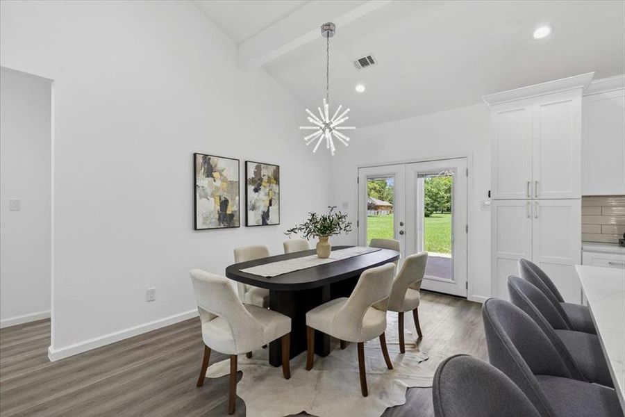 Dining area featuring vaulted ceilings with exposed beams and a modern sputnik chandelier