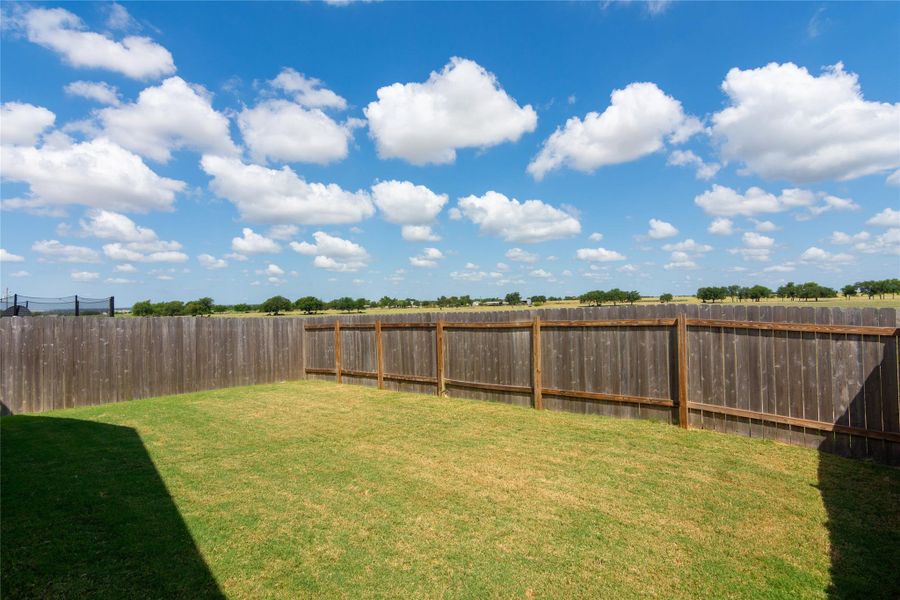 Fenced backyard with natural wood privacy fencing and expansive green space
