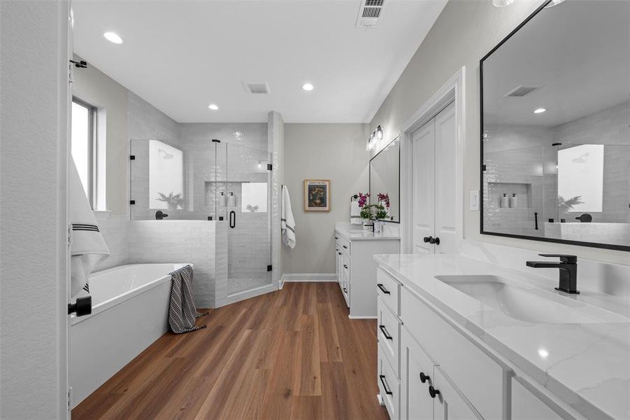 Bathroom with a shower stall, two vanities, a freestanding tub, dark wood-style flooring, and recessed lighting Bathroom with a shower stall, two vanities, a freestanding tub, dark wood-style flooring, and recessed lighting