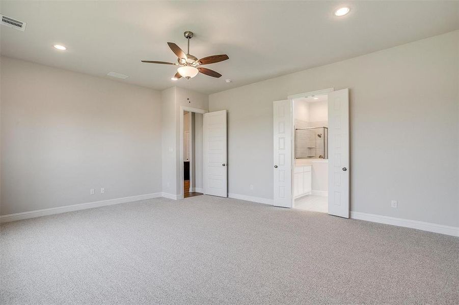 Unfurnished bedroom with light carpet, ceiling fan, and ensuite bathroom