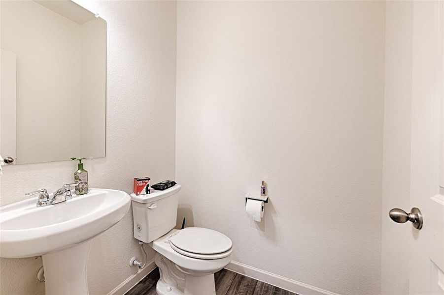 Half bathroom featuring dark wood finished floors and a textured wall Half bathroom featuring dark wood finished floors and a textured wall