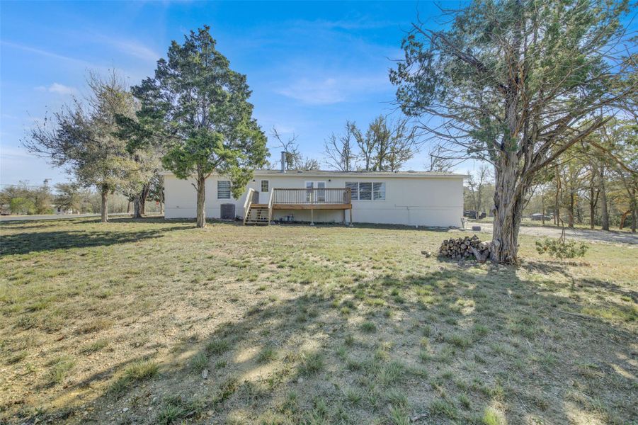 Rear view of property featuring a lawn and a deck