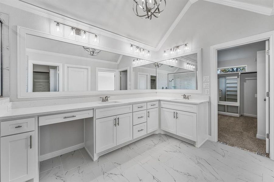 Full bath with a spacious closet, lofted ceiling, double vanity, crown molding, and a chandelier