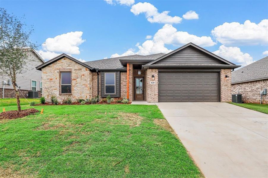 View of front of home with a garage, cooling unit, and a front yard