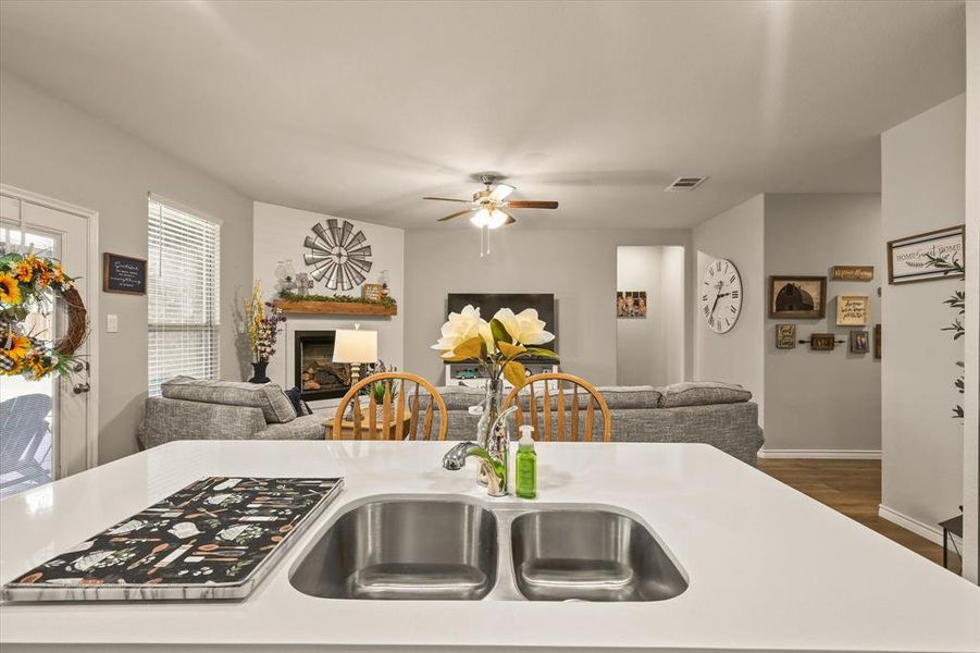 Kitchen with open floor plan, light countertops, a fireplace, wood finished floors, and ceiling fan Kitchen with open floor plan, light countertops, a fireplace, wood finished floors, and ceiling fan