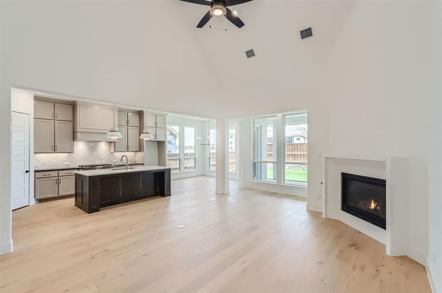 Kitchen featuring high vaulted ceiling, light wood-type flooring, a kitchen island with sink, and gray cabinets