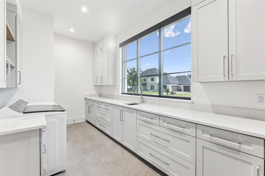 Kitchen featuring white cabinetry, sink, light stone countertops, light tile patterned floors, and independent washer and dryer