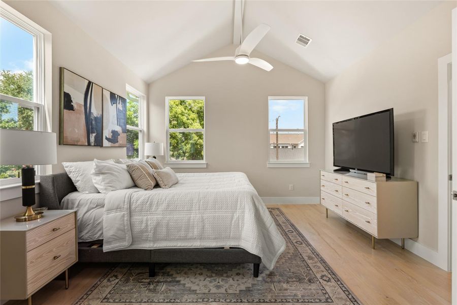 Another view of the primary suite highlighting the vaulted ceilings, custom windows & modern ceiling fan that together create a bright, tranquil atmosphere.