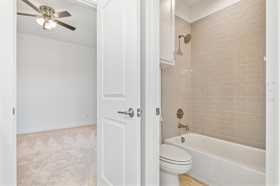 Bathroom with ceiling fan, toilet, and tiled shower / bath Bathroom with ceiling fan, toilet, and tiled shower / bath