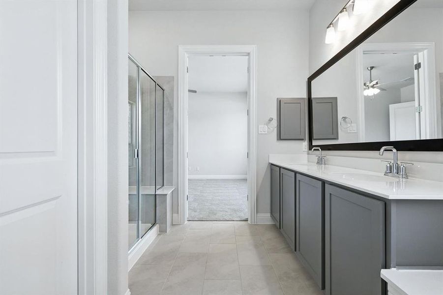 Full bathroom with double vanity, a stall shower, a ceiling fan, and tile patterned floors Full bathroom with double vanity, a stall shower, a ceiling fan, and tile patterned floors