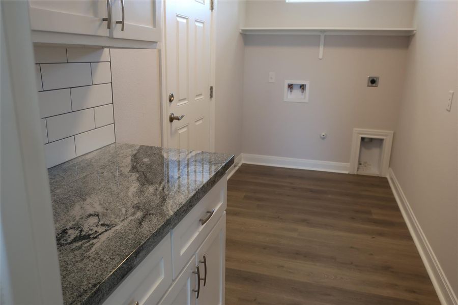 Clothes washing area featuring washer hookup, dark wood-type flooring, baseboards, and hookup for an electric dryer Clothes washing area featuring washer hookup, dark wood-type flooring, baseboards, and hookup for an electric dryer